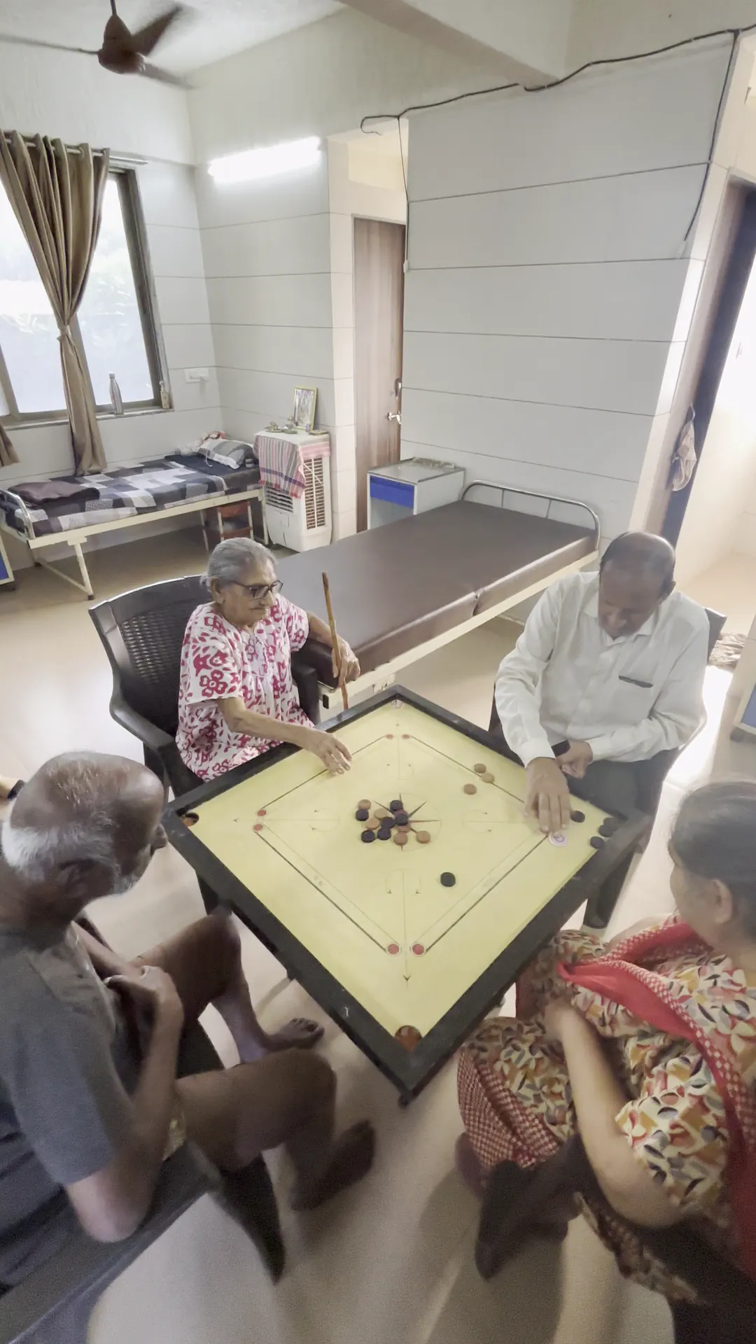 Residents seated around a carrom board, playing together