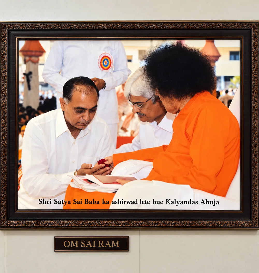 A framed photograph at Vrudhashram of Shri Satya Sai Baba giving his blessing to Kalyandas Ahuja, with a plaque below reading Om Sai Ram
